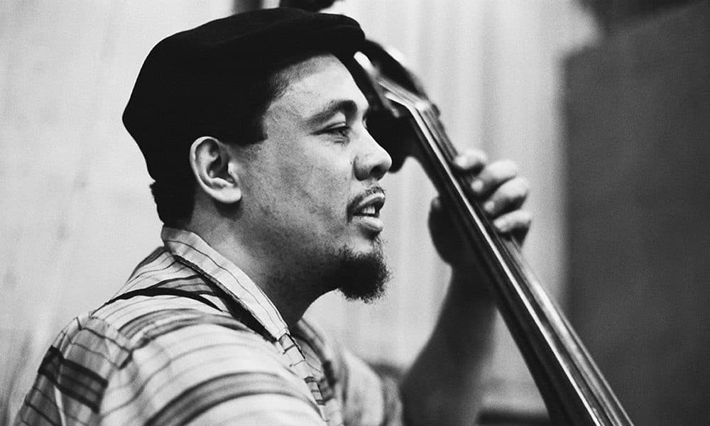 Black-and-white photograph of Charles Mingus in a cap playing an upright bass