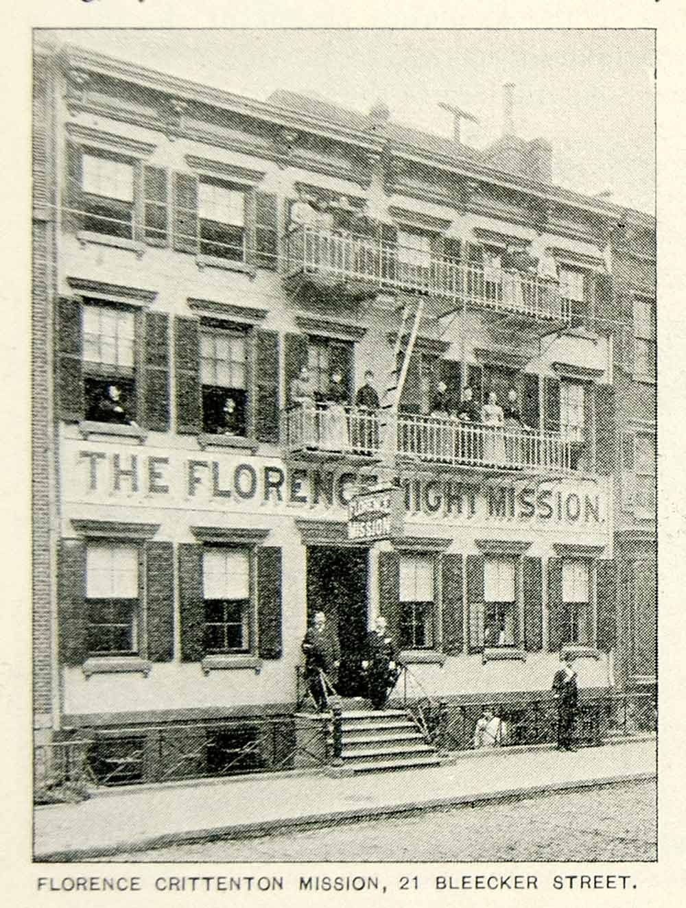 Front facade of a three-story brick building with the words THE FLORENCE NIGHT MISSION painted on the ground level. The building has large windows on each floor, metal railings on two upper-level balconies, and a recessed entrance at street level with steps leading up to it. A few people stand near the entrance.